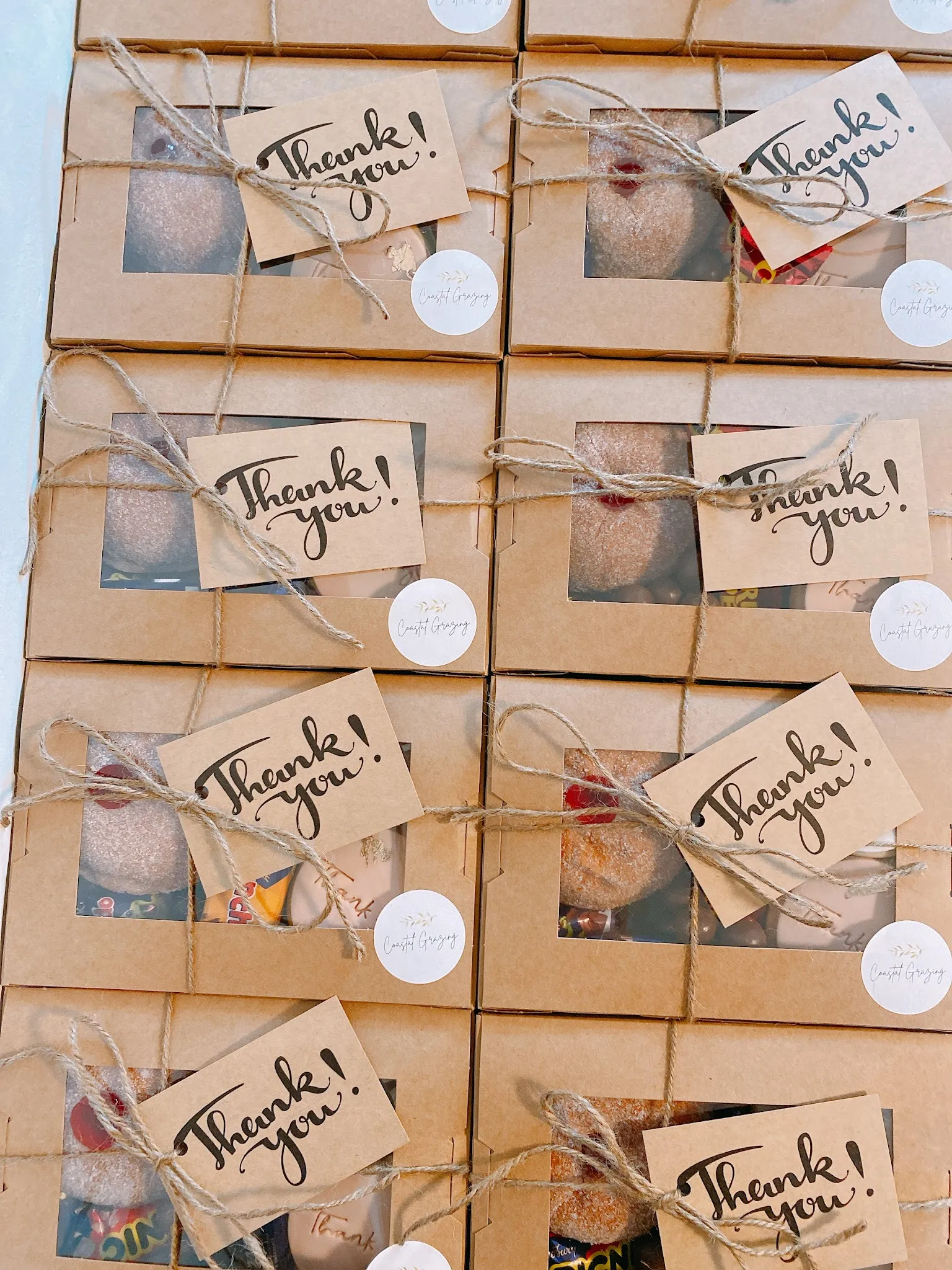 Grid of kraft gift boxes tied with twine and Thank You tags, each containing a grazing box