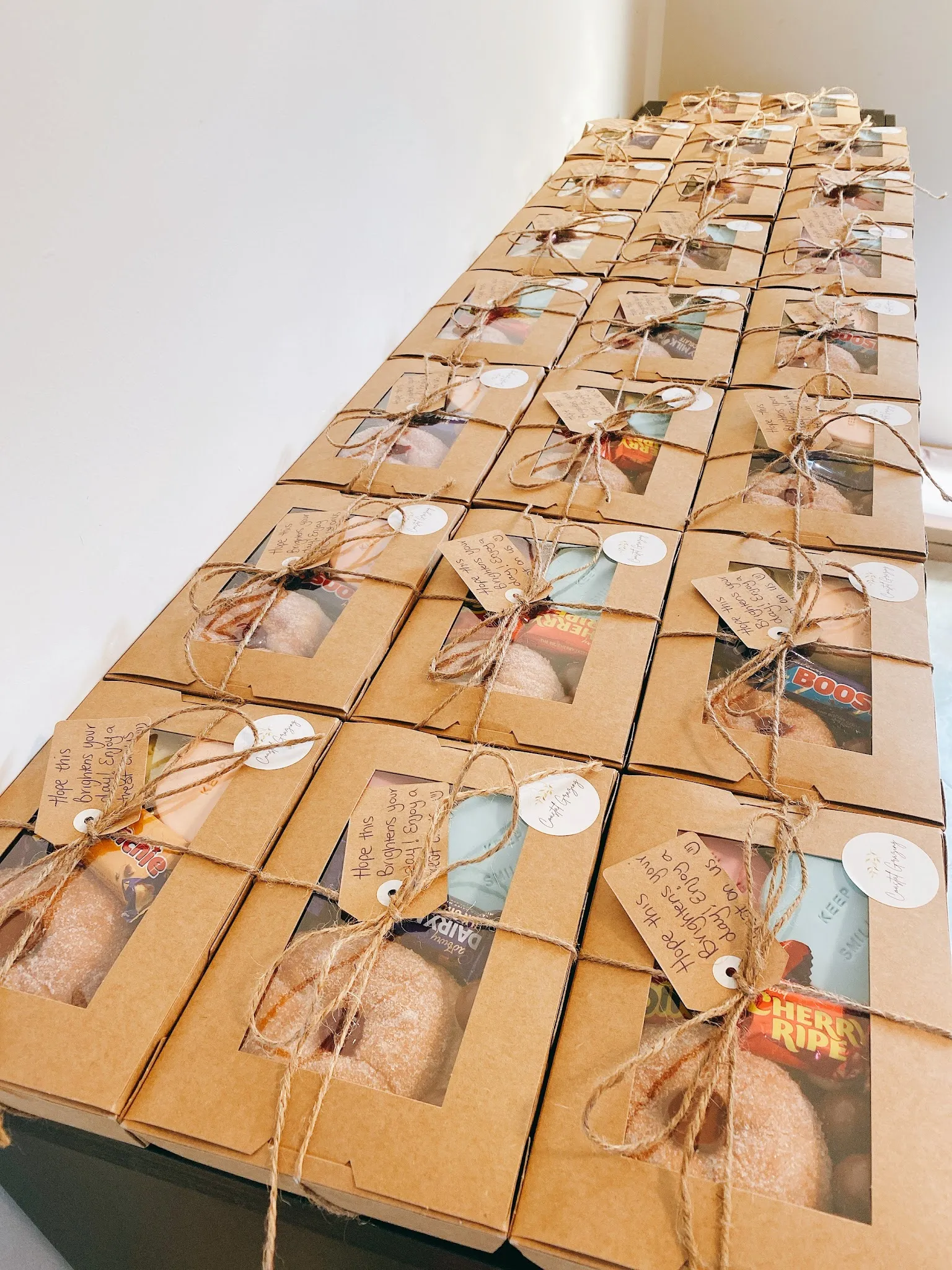 Rows of 30+ kraft grazing boxes with twine tags showing a large bulk order in preparation